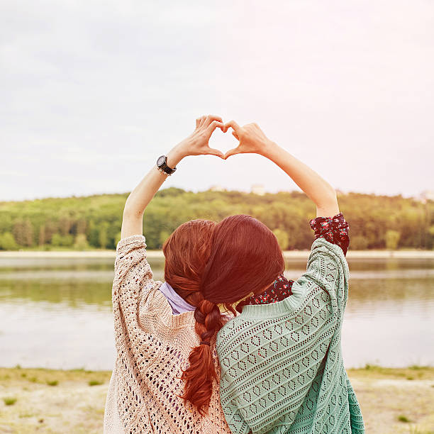 istock two sisters with interwoven hairs making heart above their heads 475666958