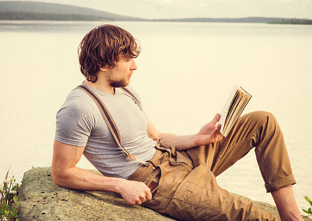 istock Young Man reading book outdoor 475669548