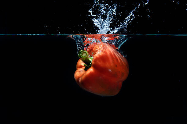 sweet pepper drop into water on black background.