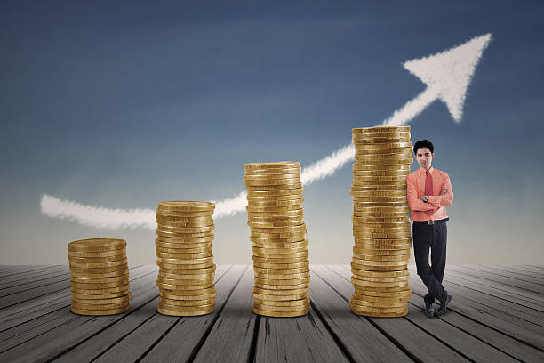 istock Businessman standing next to gold coins growth chart 475672544