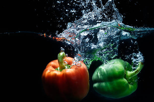 sweet pepper drop into water on black background.