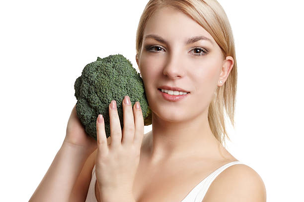 istock blonde woman with green broccoli 475689773