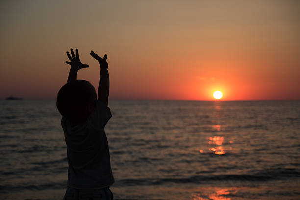 istock Little boy standing back and watching the sunset 475693232