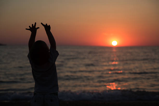 istock Little boy standing back and watching the sunset 475693252