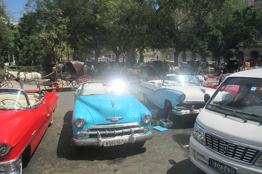 Havana, Сuba - April 6, 2015: Classic American cars parked in old town Havana in Cuba. Oldsmobile cars are often used as a tourist taxis in Cuba. Photo depicts taxi drivers waiting for tourists.