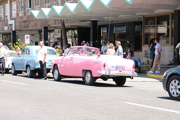 Havana, Сuba - April 7, 2015: Classic American cars parked in old town Havana in Cuba. Oldsmobile cars are often used as a tourist taxis in Cuba. Photo depicts taxi drivers waiting for tourists.