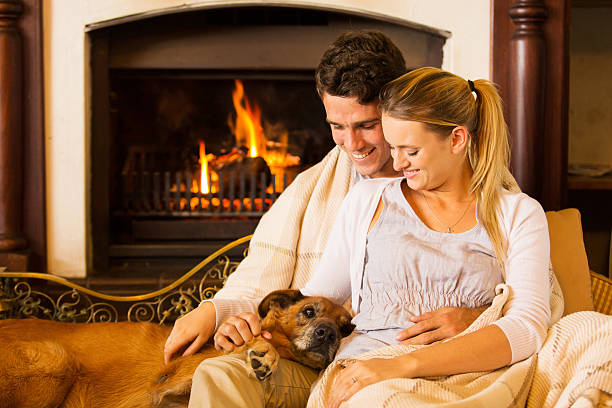 jeune couple assis près de la cheminée avec leur chien - blanket fireplace winter women photos et images de collection