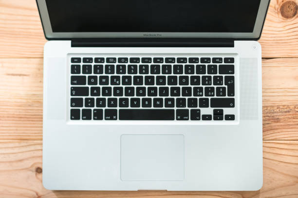 Florence, Italy - May 23, 2015: Close up of an Apple Macbook Pro silver 15 inch computer keyboard withe the trackpad on the desk made by wood. Apple is one of the leader of technology products on all over the world. Studio shot.