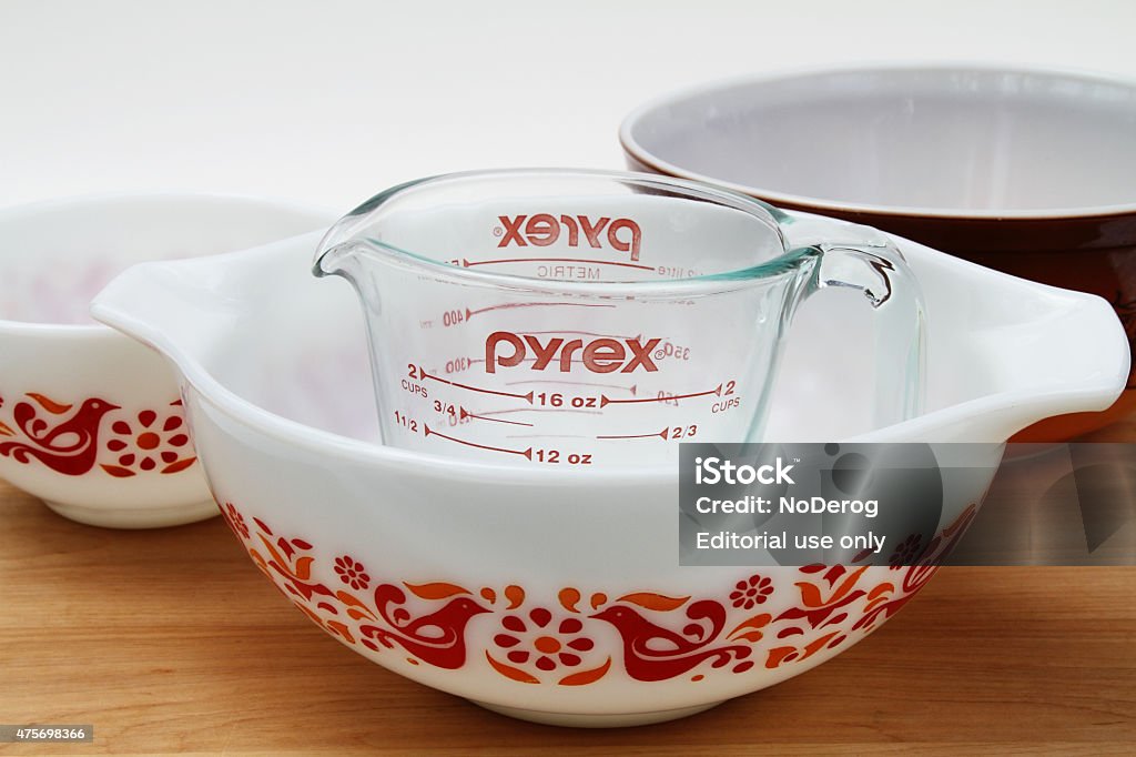 Pyrex measuring cup and mixing bowls West Palm Beach, USA - May 30, 2015: A PYREX clear glass measuring cup with several vintage Pyrex mixing bowls. The white bowls feature the friendship design. Pyrex recently celebrated its 100th anniversary since it was introduced by Corning in 1915. The brand is now produced by World Kitchen LLC, a Corning spinoff.  Crockery Stock Photo