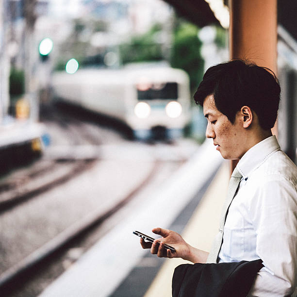 empresário espera de um trem na estação. - rush hour commuter on the phone tokyo prefecture - fotografias e filmes do acervo