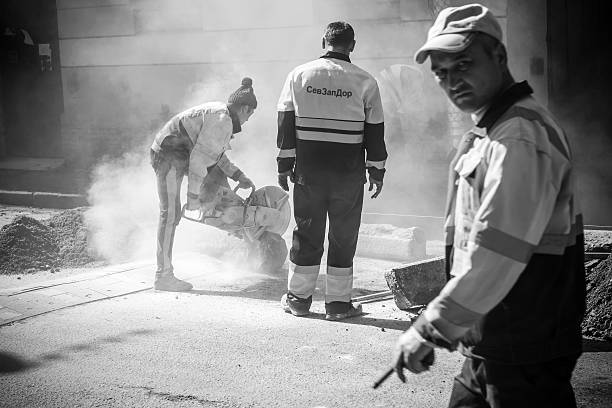 Saint-Petersburg, Russia - May 23, 2015: men at work, urban road under construction, sawing of a roadside border stones