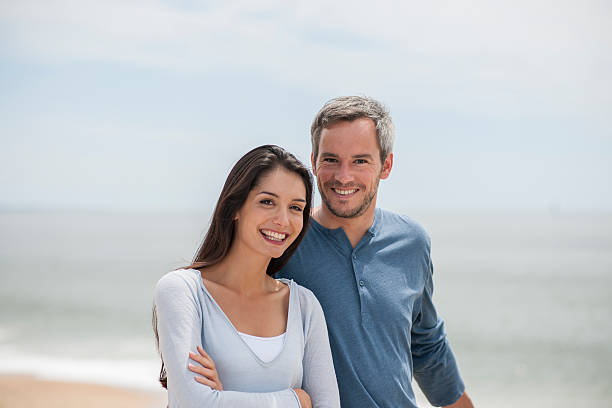 istock couple on the beach smiling and looking at camera 475703190
