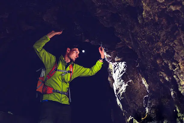 Photo of Man exploring underground dark cave tunnel