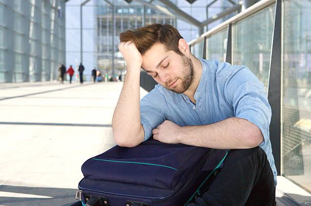 istock Tired man with bag sleeping at airport 475706420