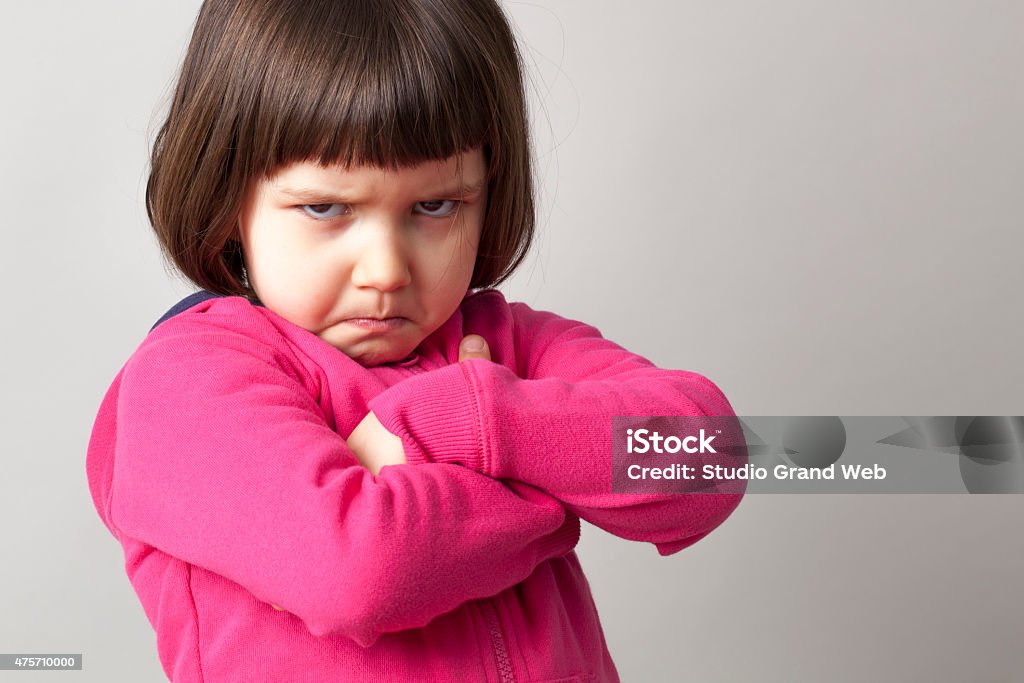 frustrated young child sulking with crossed arms and dirty look unhappy boyish 4-year old girl expressing disagreement with body language Child Stock Photo