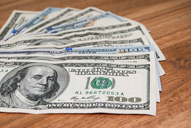 istock 100 US dollars banknotes on wooden background 475710082