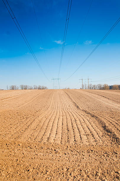 istock spring plowed field, over the field of high-voltage power line 475713526