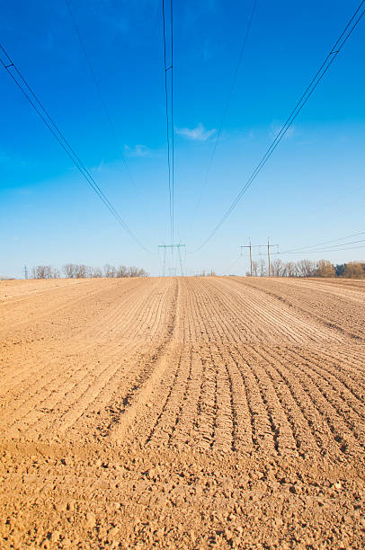 istock spring plowed field, over the field of high-voltage power line 475713528