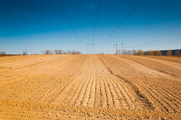 istock spring plowed field, over the field of high-voltage power line 475713530