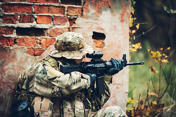 istock soldier with rifle in the forest 475715270