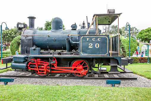 Lima, Peru - January 21, 2015: Vintage Peruvian steam train in Lima park Parque de la Amistad. People are pictured sitting in the background
