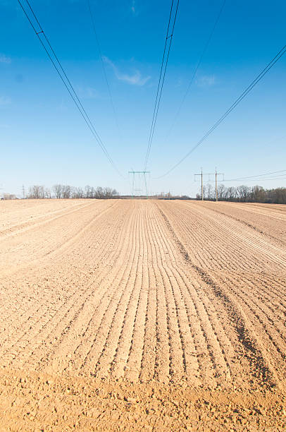 istock spring plowed field, over the field of high-voltage power line 475716456