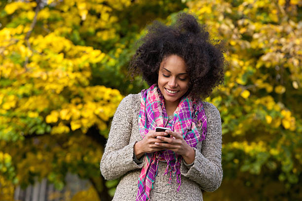 feliz jovem mulher lendo mensagem de texto no telefone celular - telephone nature mobile phone autumn - fotografias e filmes do acervo