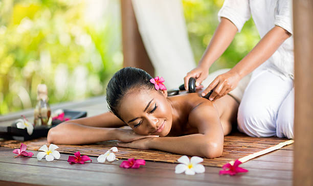 istock Young woman enjoying a hot stone massage 475726374