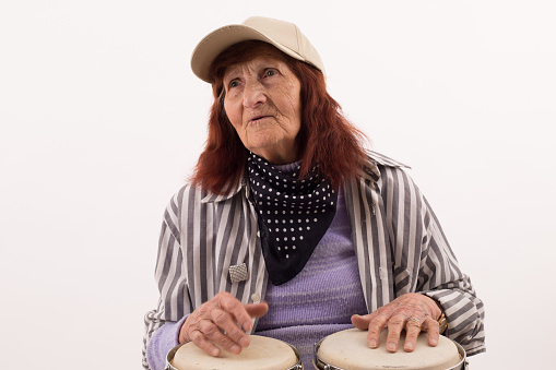 Funny elderly lady makes music with a wooden bongo.