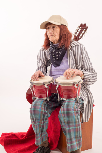 Funny elderly lady makes music with a wooden bongo.