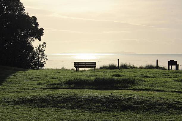 istock Empty park bench looking at the sun on the horizon 475733782
