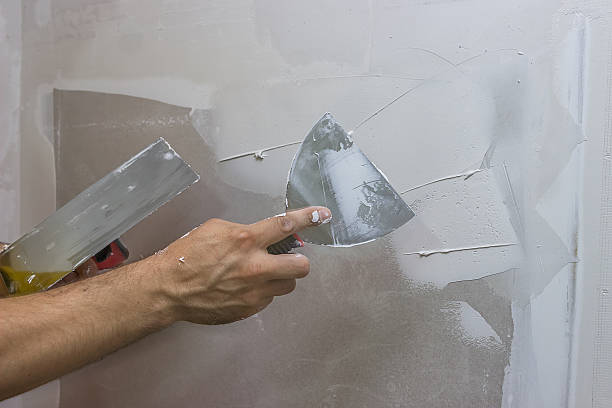 man hand with trowel plastering a wall man hand with trowel plastering a wall, skim coating plaster walls putty stock pictures, royalty-free photos & images