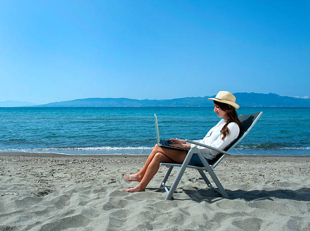istock Woman with laptop on the beach 475735198
