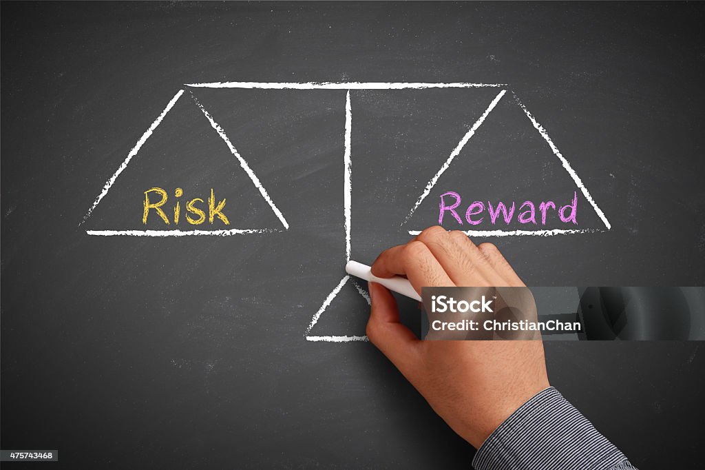 Risk and reward balance Hand with chalk is drawing Risk and reward balance scale on the chalkboard. Risk Stock Photo