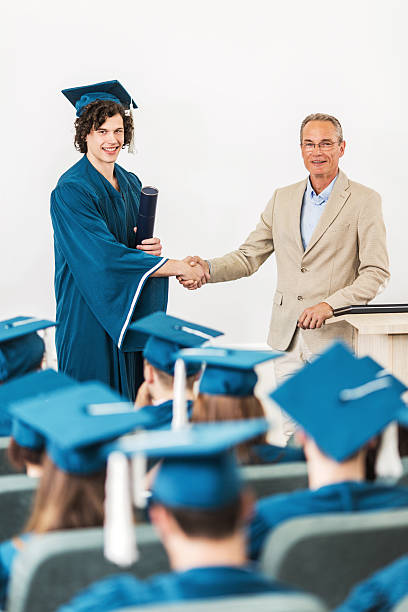 istock Graduation student shaking hands with professor and looking at camera. 475746874