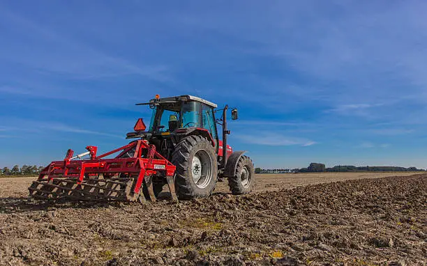 Farming in the Netherlands, Tractor with Plough in a Field under Blue Sky