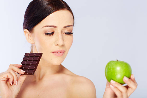 istock woman with a apple and chocolate in her hand 475750632