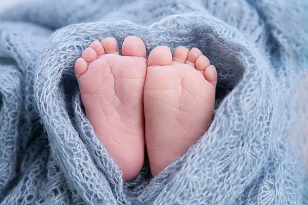 Little toes, baby feet wrapped in a heart blanket