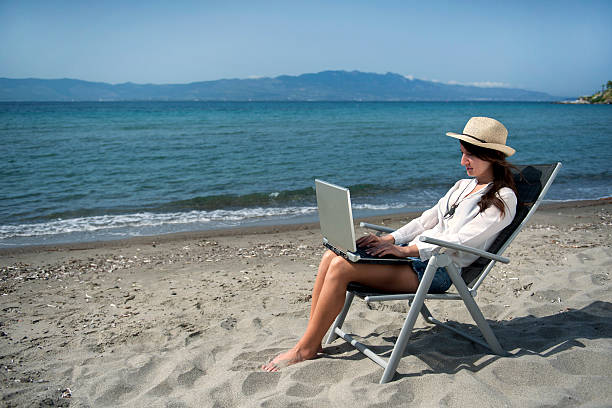 istock Woman with laptop on the beach 475756530