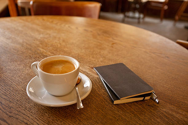 istock Coffee cup, wooden table, closed notepad journal, warm cafeteria restaurant, 475762023