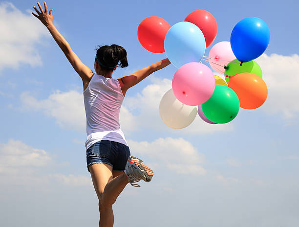 istock young asian woman running with colored balloons 475763090