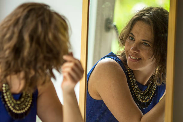 istock Young woman looks in the mirror. 475763576