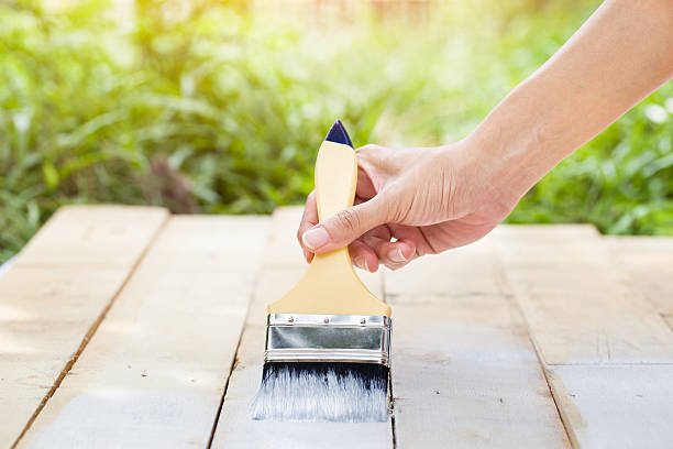 istock hand worker holding brush painting white on wood texture 475771486