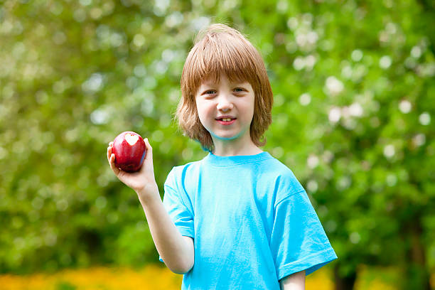 istock Boy with Red Apple Showing Heart Shaped Bite Off 475772570
