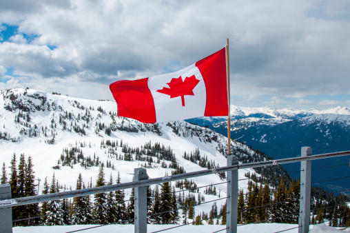 A Canadian flag flaps in the breeze on top of a snow covered Whistler Mountain in British Columbia, Canada