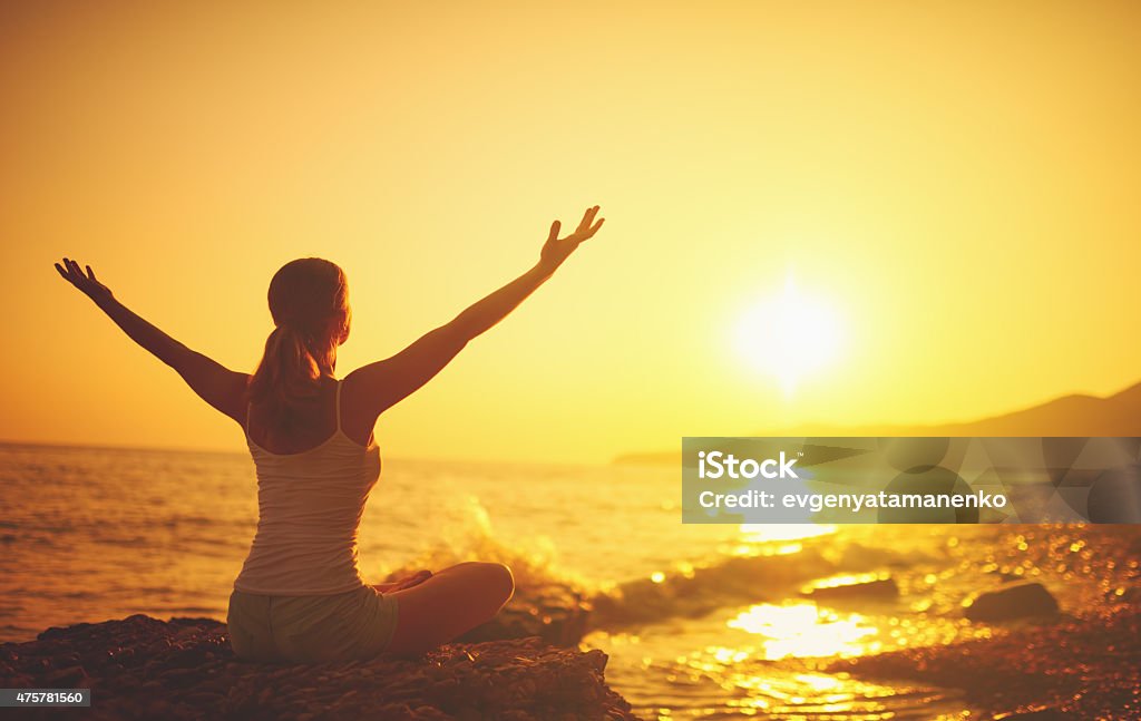 yoga at sunset on  beach. woman doing yoga yoga at sunset on the beach. woman doing yoga, performing asanas and enjoying life on the sea Zen-like Stock Photo