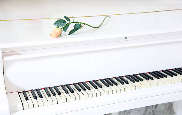 istock White piano with beautiful yellow rose 475787229