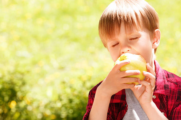 istock Close up of little boy biting off apple 475788344