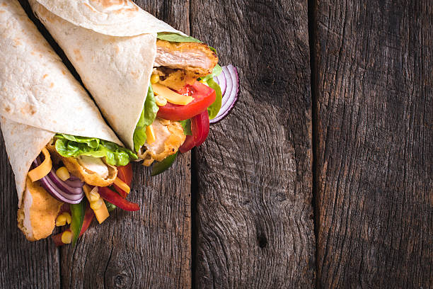 Tortilla sandwiches with fried chicken Tortilla sandwiches with fried chicken and vegetables on wooden background with blank space mexican culture food mexican cuisine fajita stock pictures, royalty-free photos & images