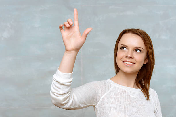 istock Young woman pointing upwards with her index finger 475796312